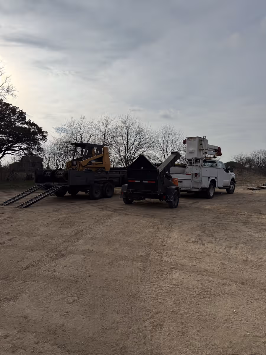 Skid steer, chipper and bucket truck loaded and staged for a job