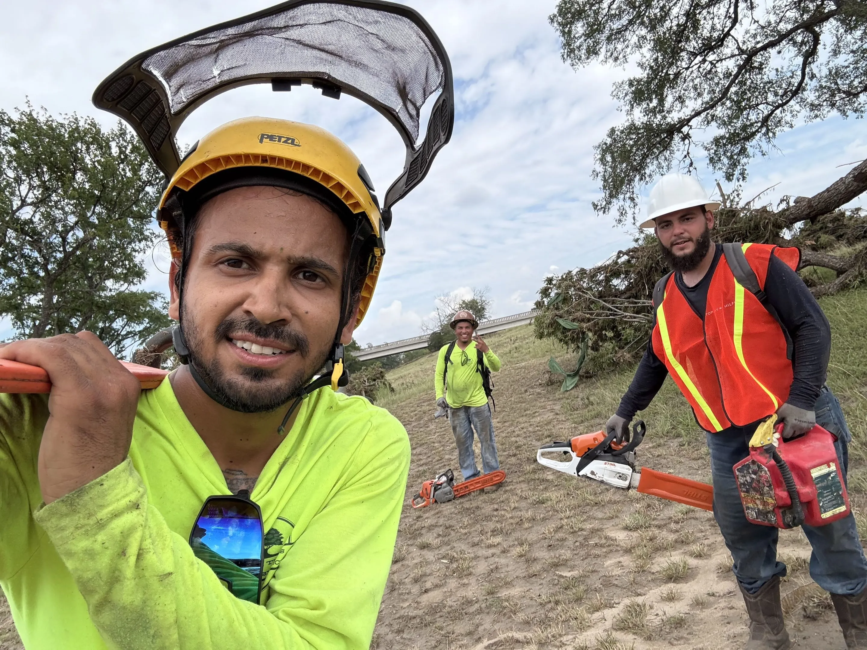 Three crew members in hi-vis and hard hats with chainsaws on a storm cleanup